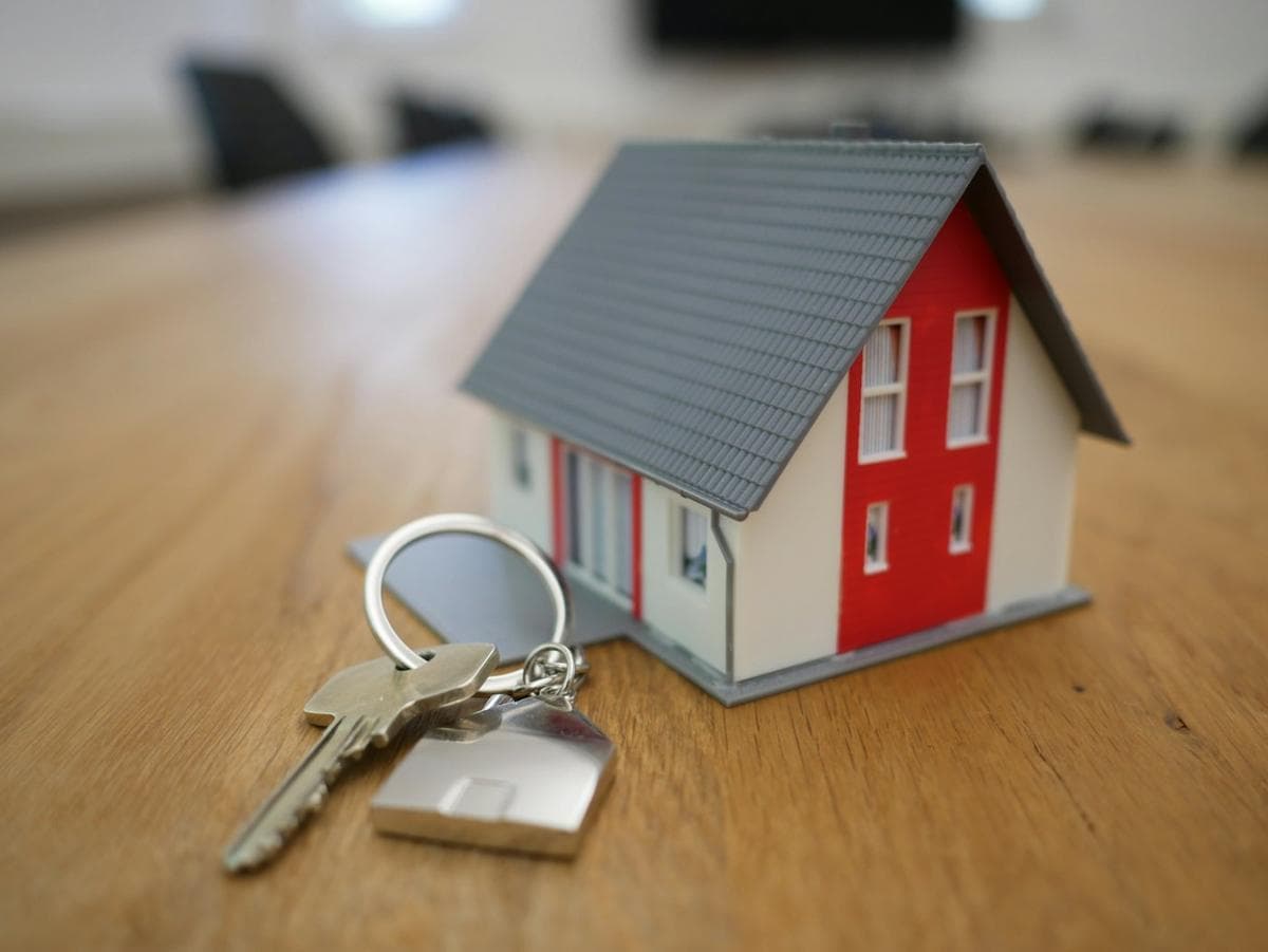 A model house held in front of a residential street.